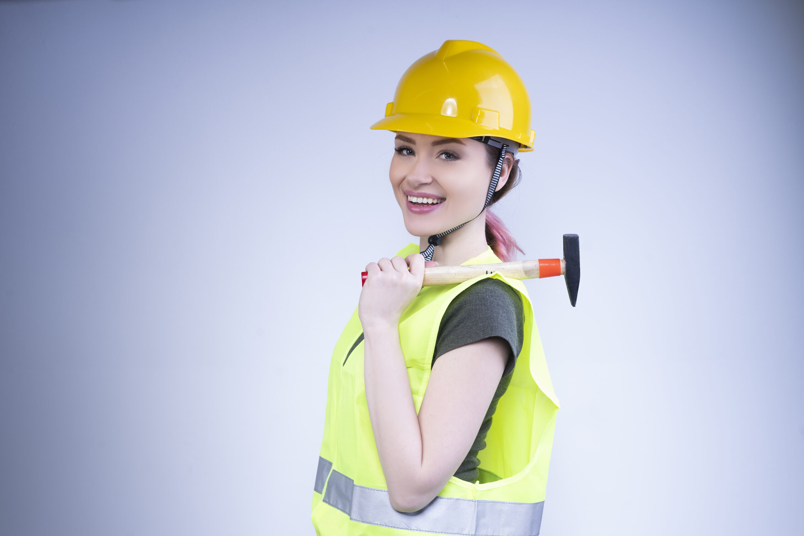 smiling woman yellow helmet stands with hammer her shoulder scaled